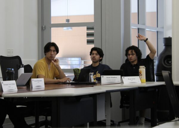 Three ASG board members seen sitting around table during meeting discussing business resolutions. Members Grant Wass and Jason Mendoza are seen engaged in the conversation, while Ryan Javier is seen raising his hand to comment.