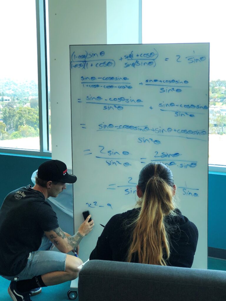 A tutor at a whiteboard tutoring a student.