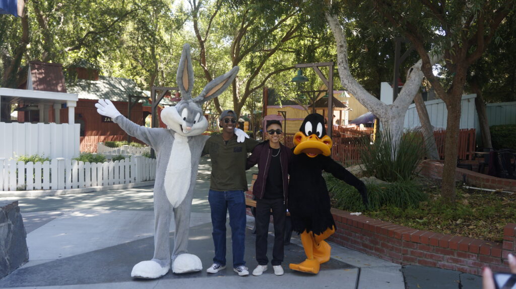 Two students posing with a bugs bunny and daffy duck costume characters. 