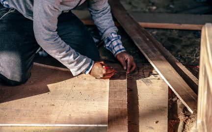 Construction worker holding a pencil and measuring different pieces of wood.