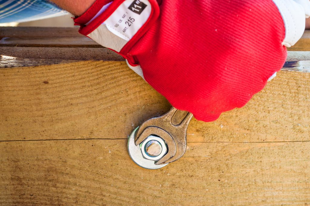 Gloved hand using a wrench being applied to a bolt 