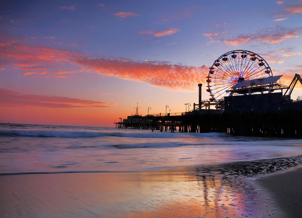 Ferris wheel on a pier with the ocean an sky reflecting the colors of sunset