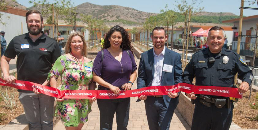 Five Palomar employees behind a red grand opening ribbon