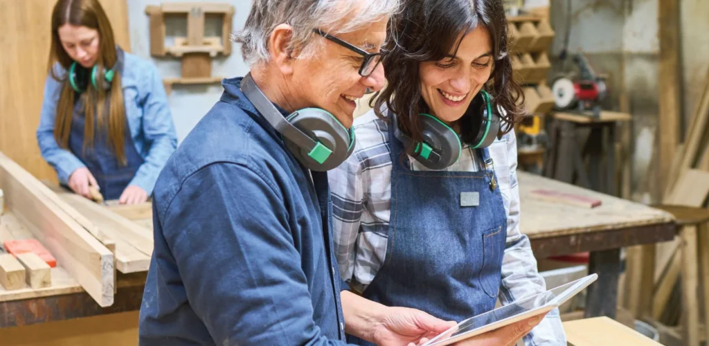 Experienced tradesperson mentoring an apprentice in a workshop.