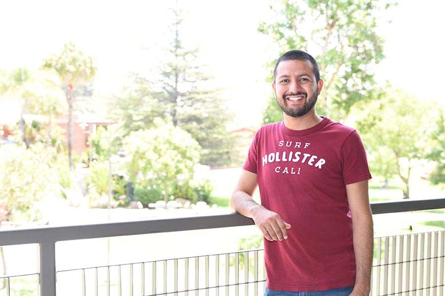 Smiling student standing against a railing.